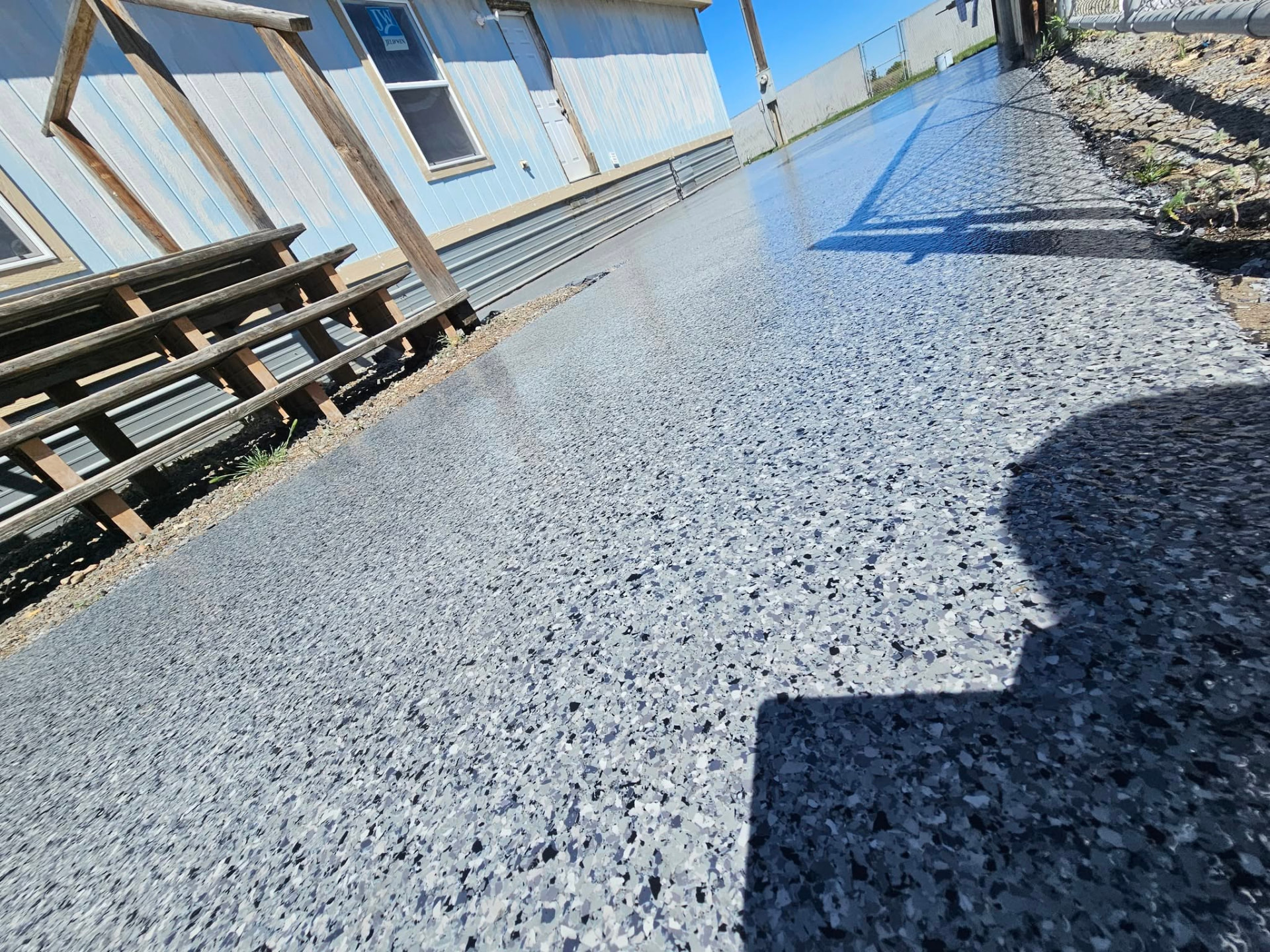 Outdoor flake epoxy walkway alongside a shop building